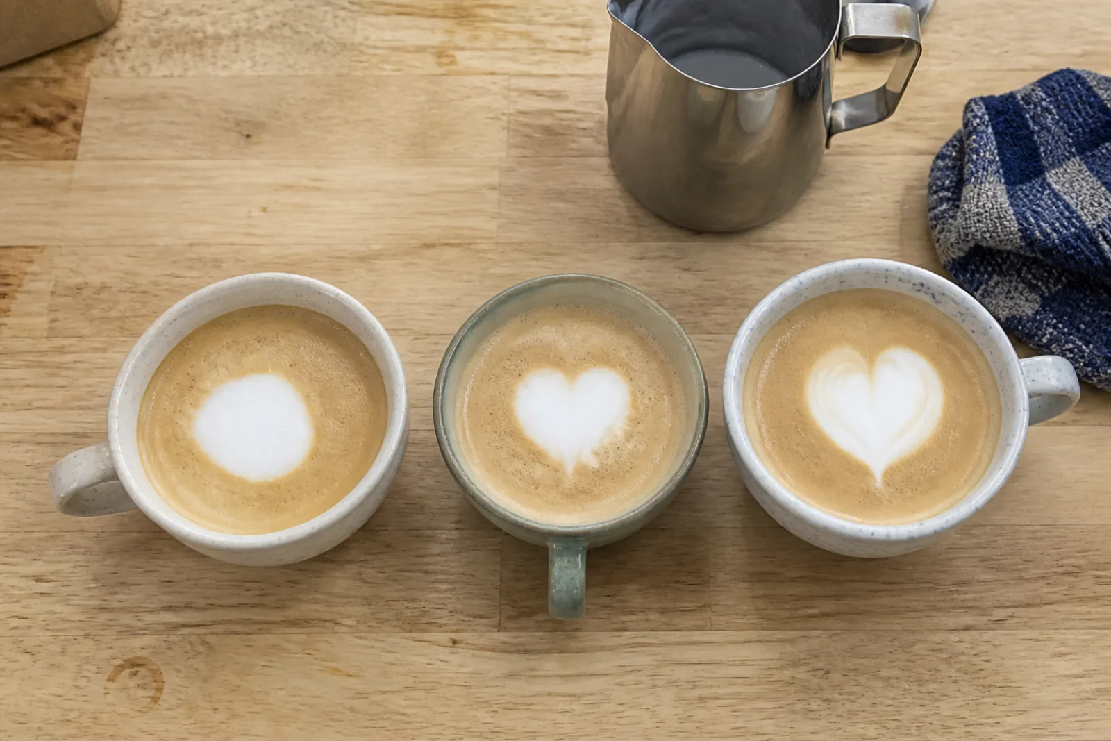 A home barista finishing the cut-through on a slightly imperfect latte art heart