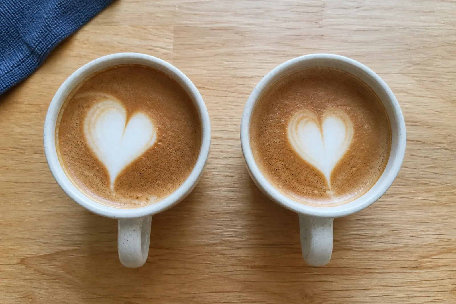 Two home-poured latte art hearts viewed from above, one slightly off-centre and one more centred