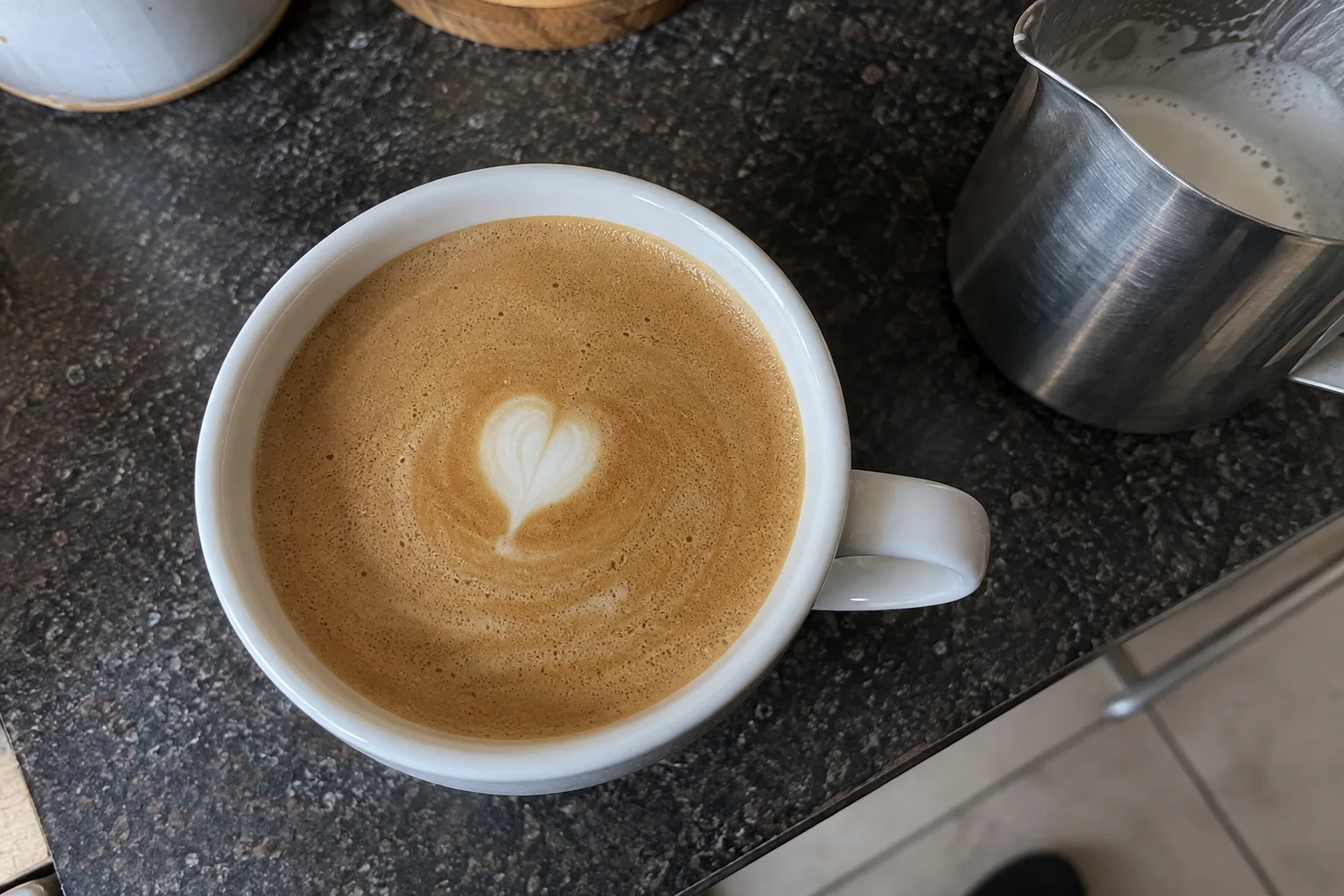 A tiny white latte art heart surrounded by a wide area of brown coffee