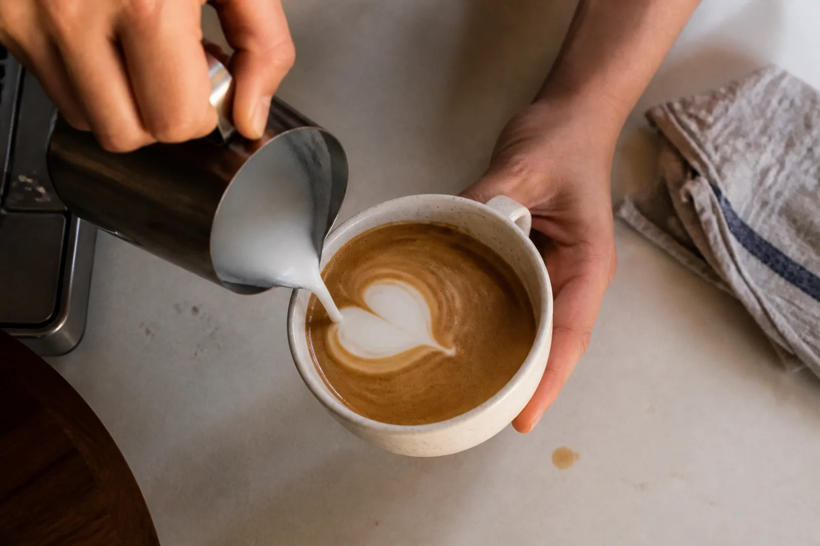 Three home latte art attempts progressing from a white blob to a clearer heart
